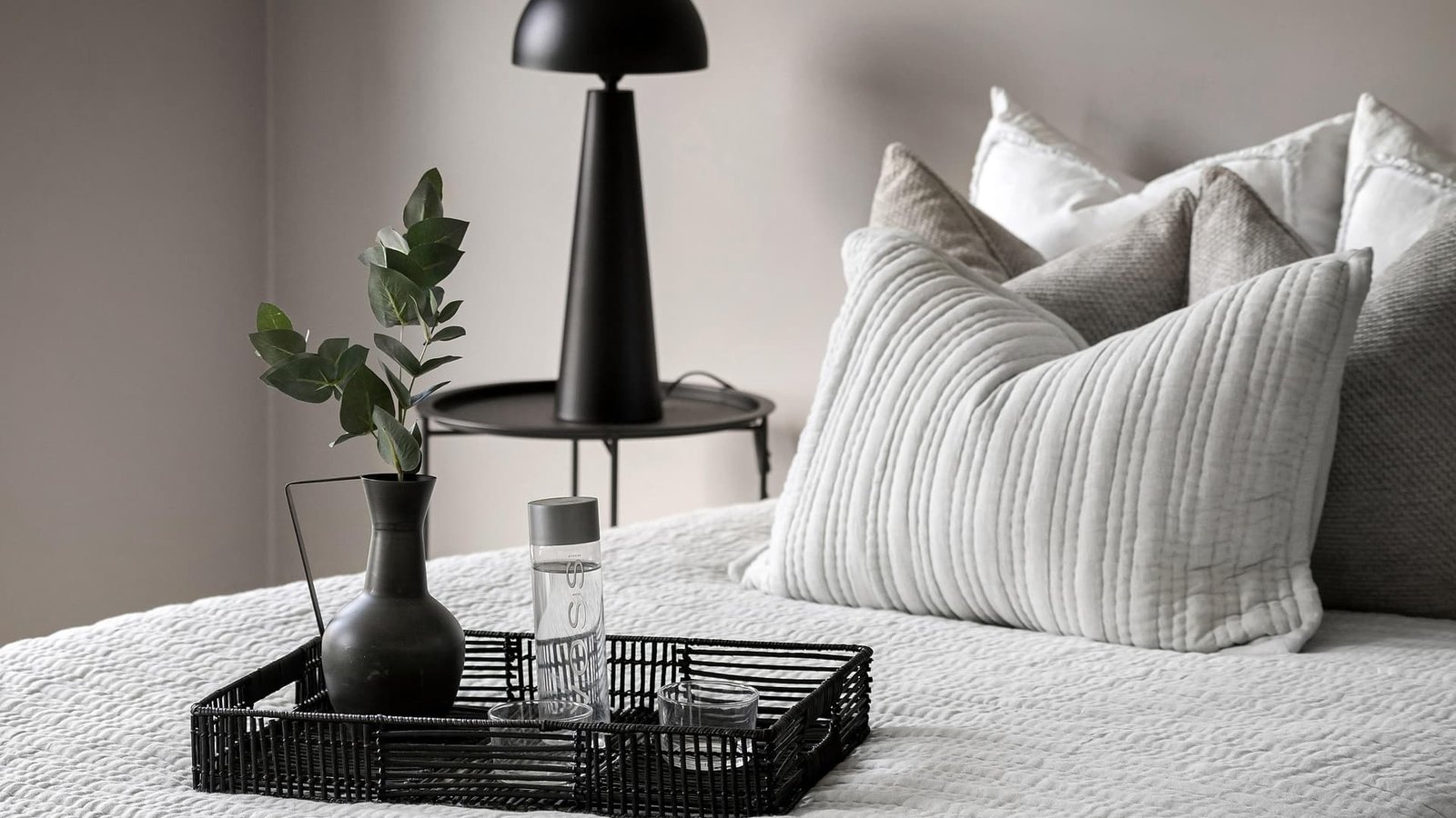 alt="Una habitacion tranquilla llena de paz, una cama arreglada con dos amohadas bien comodas, tonos blancos y grises"