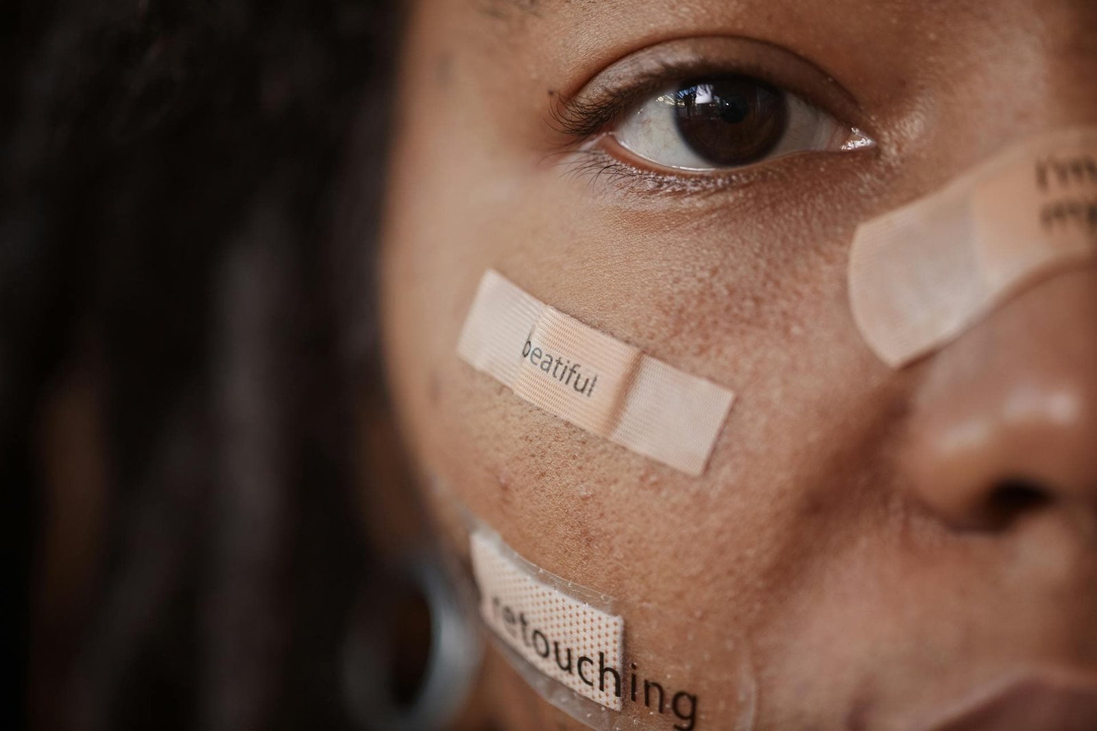 alt="Rostro de mujer, media cara con varios parches colocados en sus mejillas y nariz"