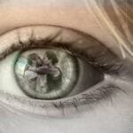 alt=" El Ojo de una niña mirando fijamente, en su interior se puede ver el reflejo de como el papa maltrata a su mama"