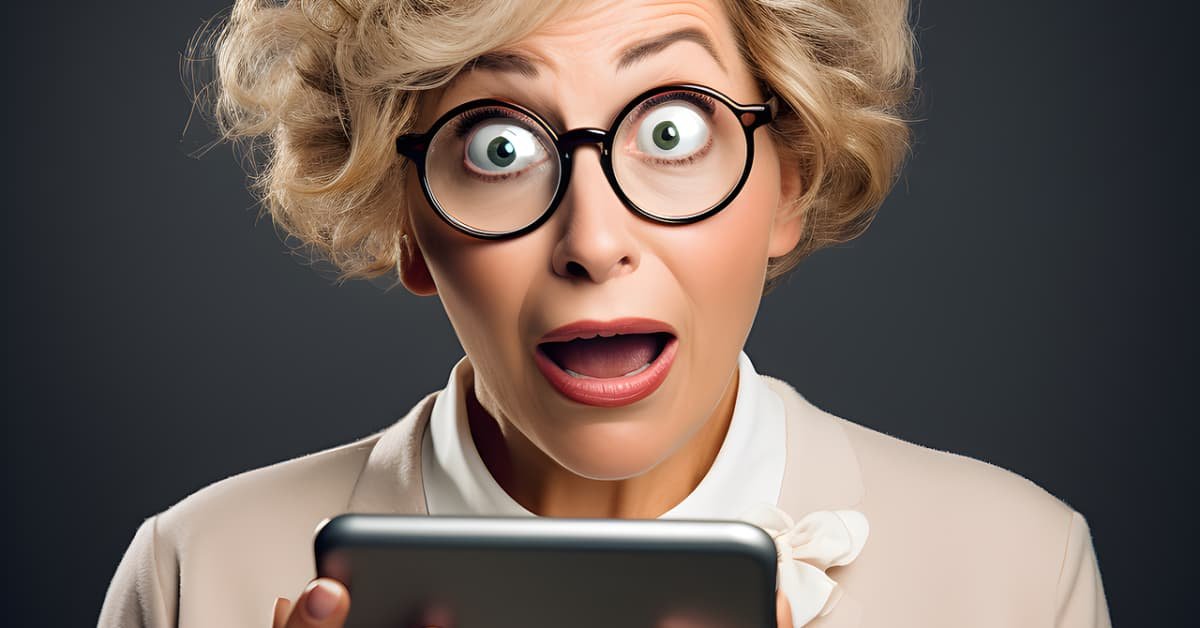 alt="Mujer de 50 años de edad con gafas y peinado sofisticado, asombrada con una tablet en la mano"