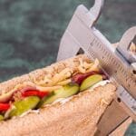 alt="Con un pie de Rey se esta midiendo el ancho de un sandwish con jaon y verduras"