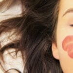 alt="Rostro de mujer con pelo suelto y corazones pintados en su cara"