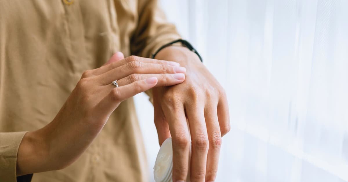 alt="Hombre delgado tocandose la parte superior de una mano como si le doliera algo"